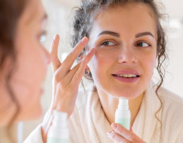 woman-applying-cream-face-while-looking-mirror.jpg